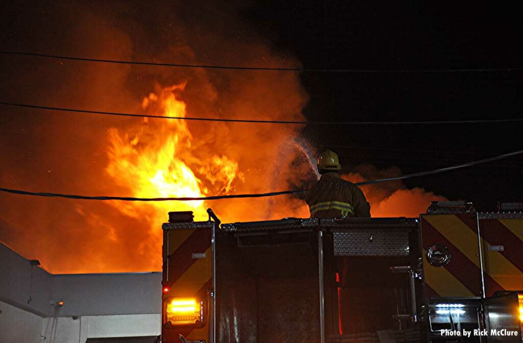 Firefighter in an apparatus using deck gun on flames in building