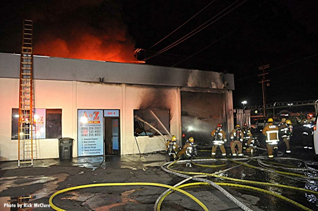 Laddered building with LAFD firefighers putting multiple hose streams into building