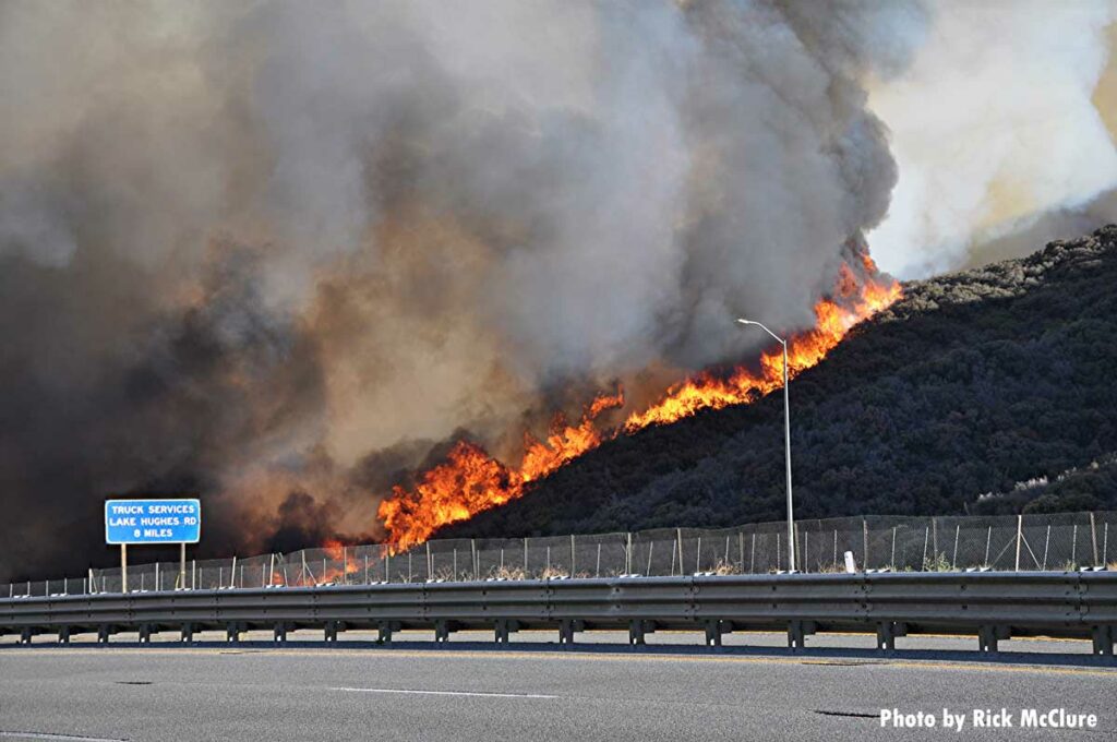 Flames tear down a hillside toward a California roadway