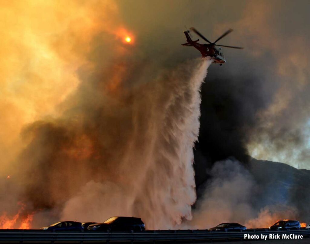 Helicopter drops retardant on wildfire near highway in California