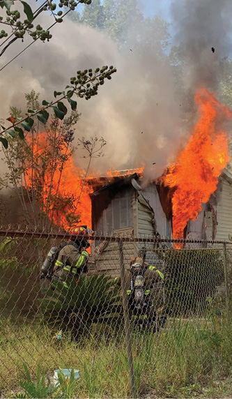 firefighters with flames blowing out of home