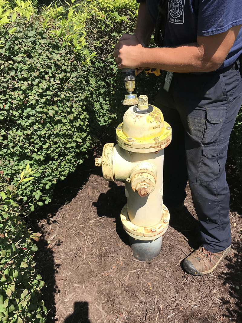 A residence has let shrubs overgrow around the fire hydrant. As crews went to clean (with a cordless drill with a wire wheel), they approached the homeowner in a respectful manner and explained what they were doing. In this case, the homeowner agreed to correct the issue. In some cases, the homeowners aren’t so agreeable, and then administrations and code officers have to get involved.