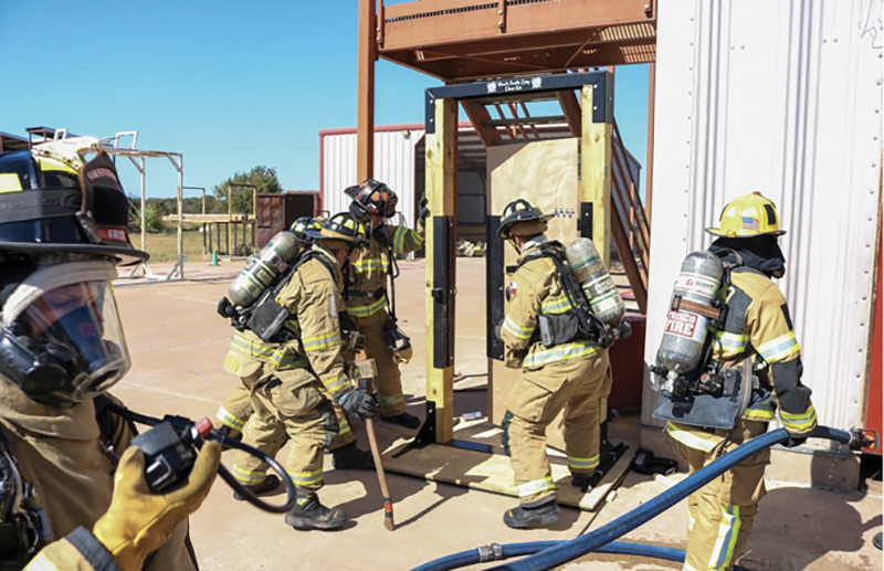 A firefighter is assigned to a force-the-door prop prior to fire attack before entering the burn building during a live fire evolution.