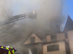 Tower ladder bucket shrouded in smoke from house fire