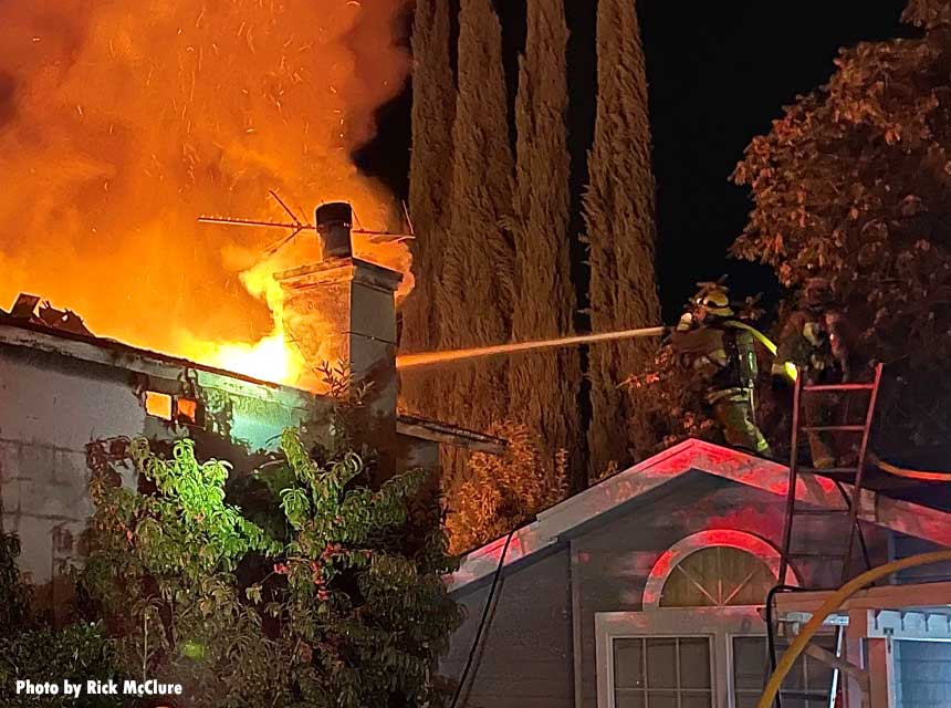 A firefighter applies an exterior stream at a structure fire