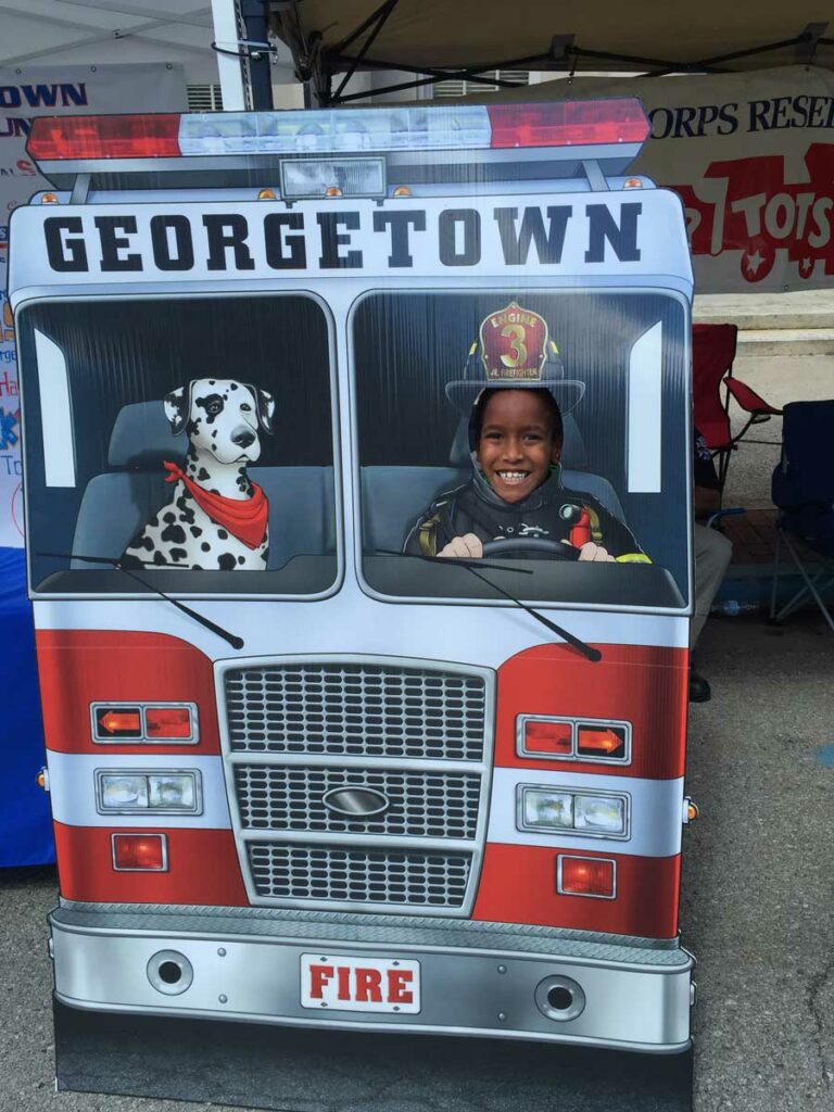 Child in cardboard cutout of fire truck