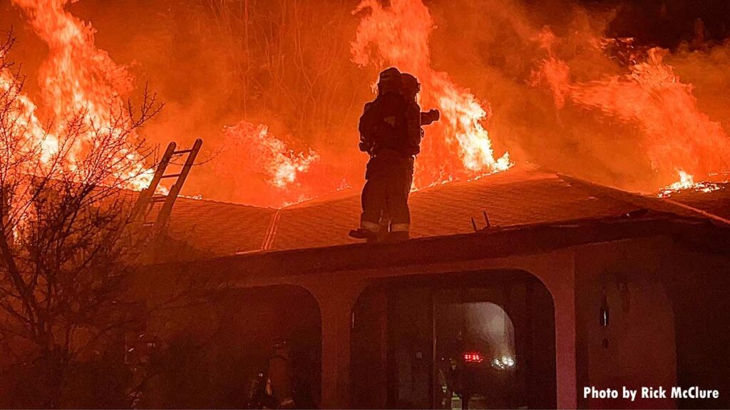 Ladder to roof with firefighters from Ventura County at fire