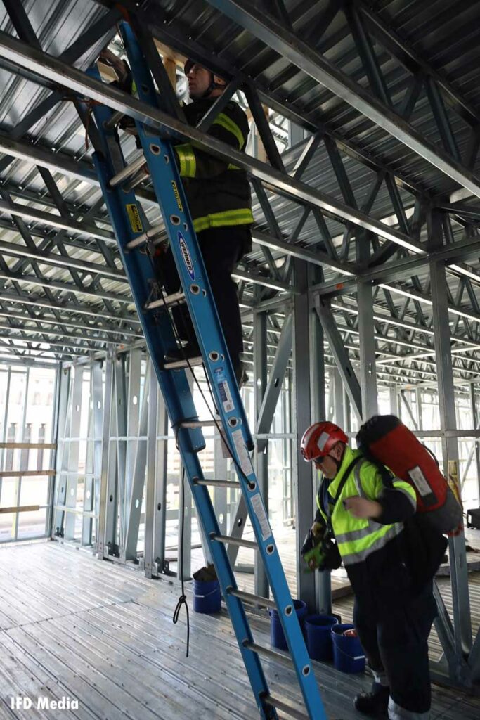 Indianapolis firefighters climb a ladder inside the building under construction