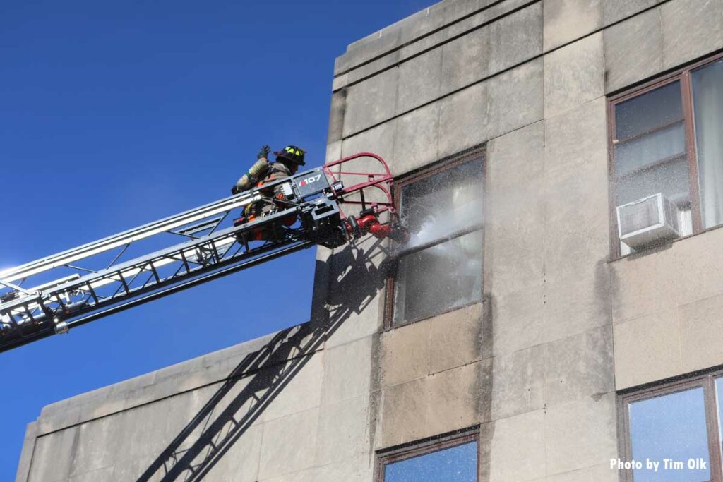 Firefighter puts aerial master stream through window of building