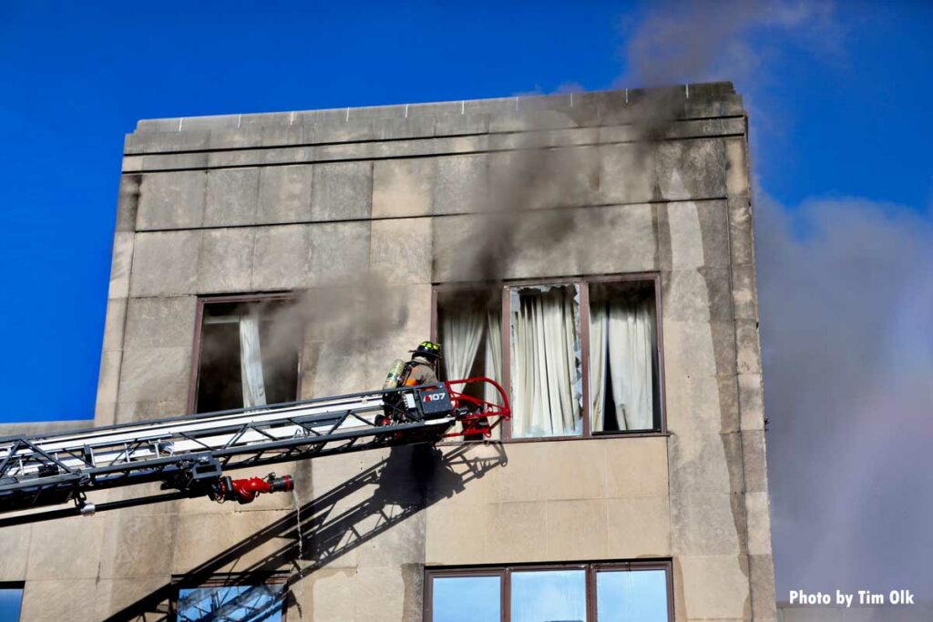 Firefighter in aerial at window of building with smoke showing