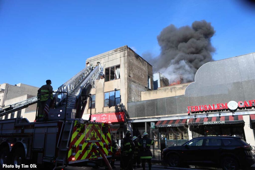 Dark black smoke at scene of fire with aerial device