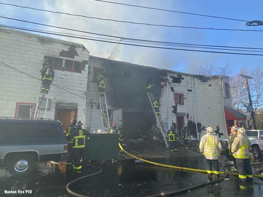 Boston firefighters on ladders at eight-alarm fire