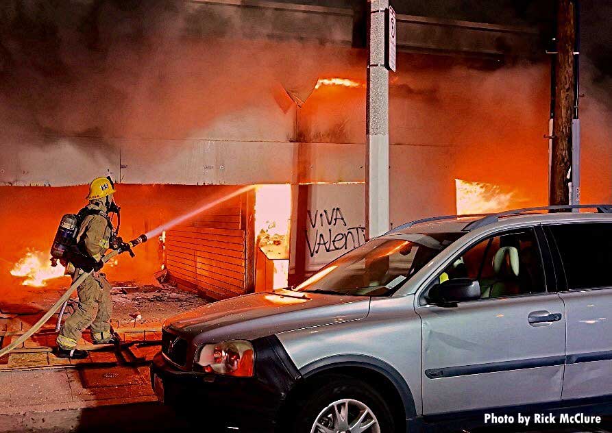 Firefighter with a hoseline putting water inside a building