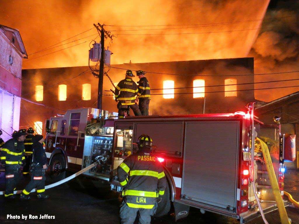 Passaic firefighters and pumper with flames in background