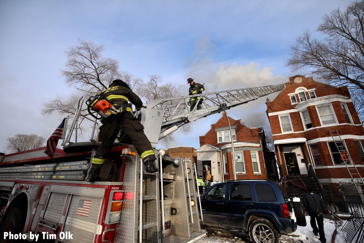 Chicago firefighters climb an aerial ladder