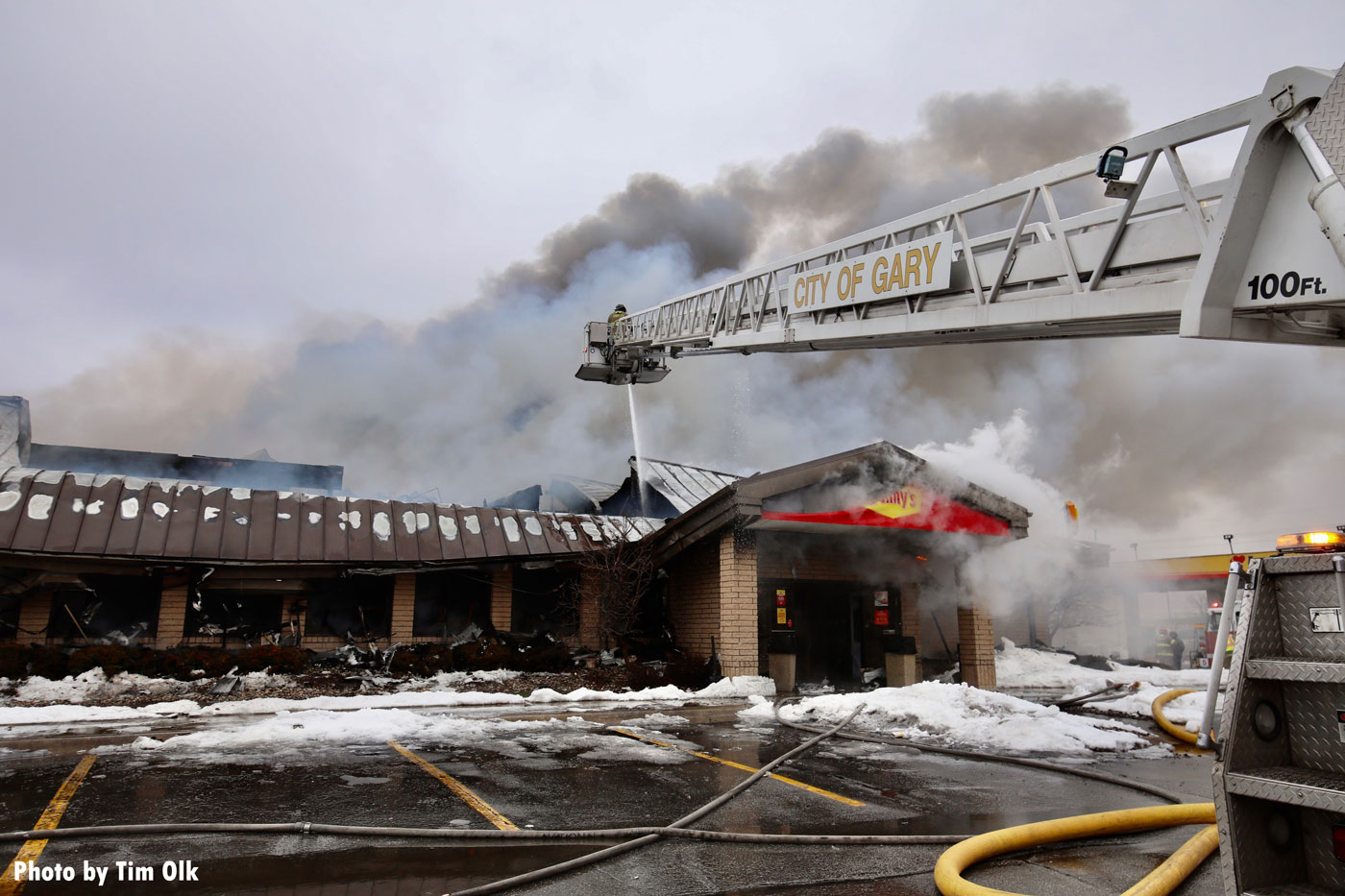 Firefighter in tower ladder bucket and smoke at truck stop fire