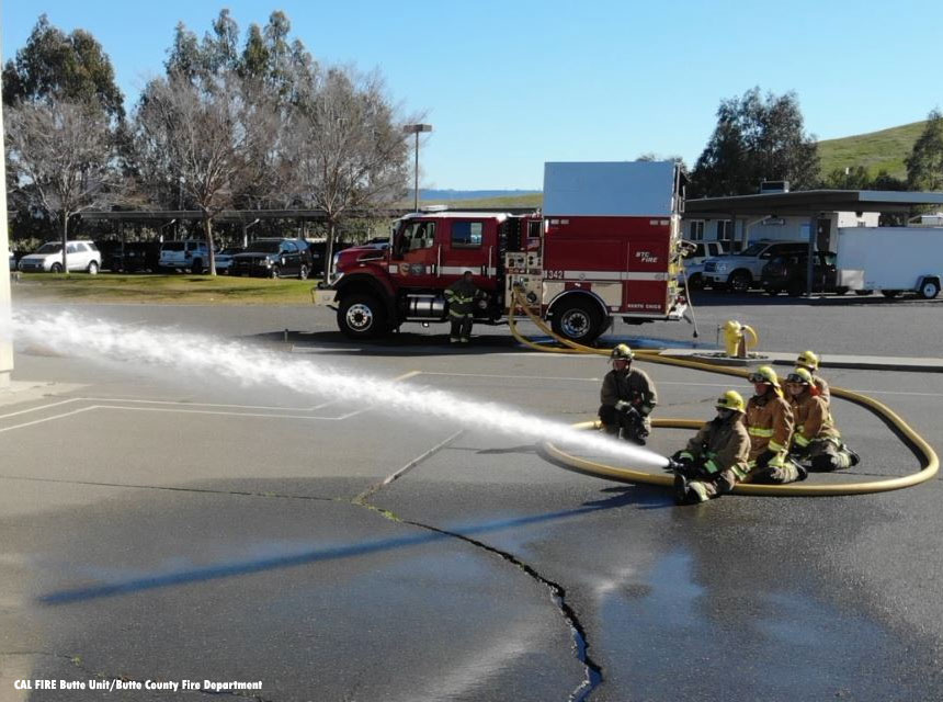 Firefighters sit on a large hoseline