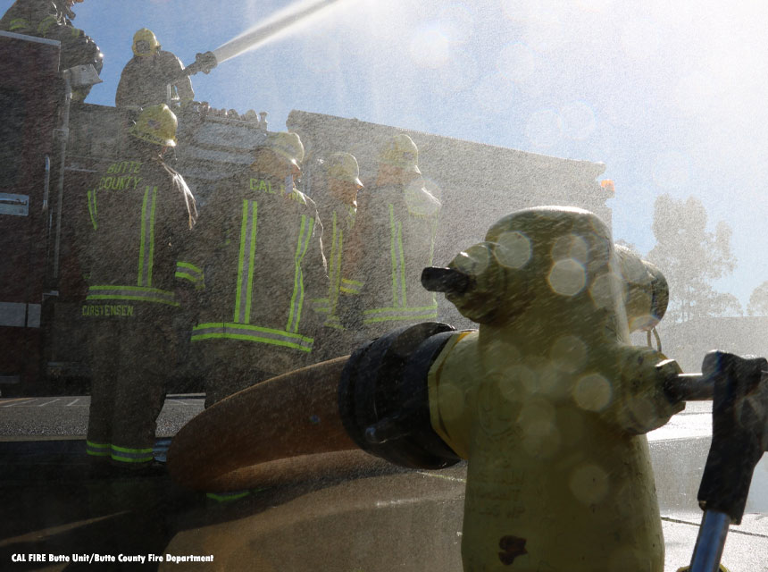 Firefighters with fire truck hose stream and fire hydrant