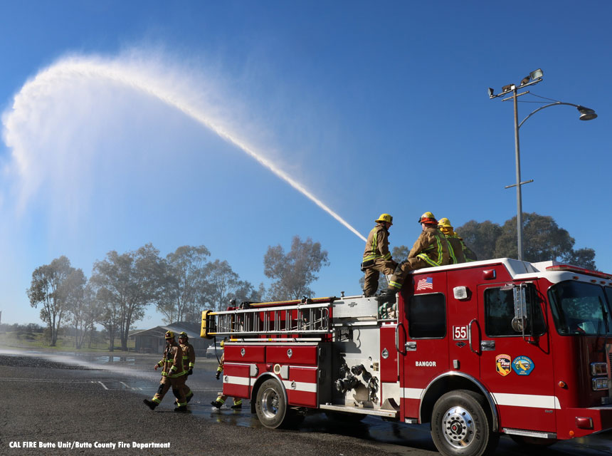 Firefighters with a hose stream off a fire truck