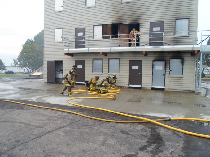 Firefighters with hoselines at live fire training building