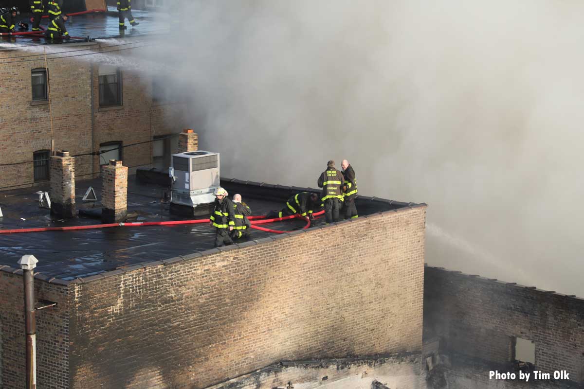 Chicago firefighters operating with hoseline on roof surrounded by smoke