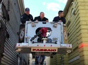 Firefighters in tower ladder bucket between two buildings