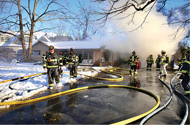 Firefighters operate at a vehicle fire in a garage in Northbrook, Illinois. The temperature is in the mid-20s; note the ice in the driveway.