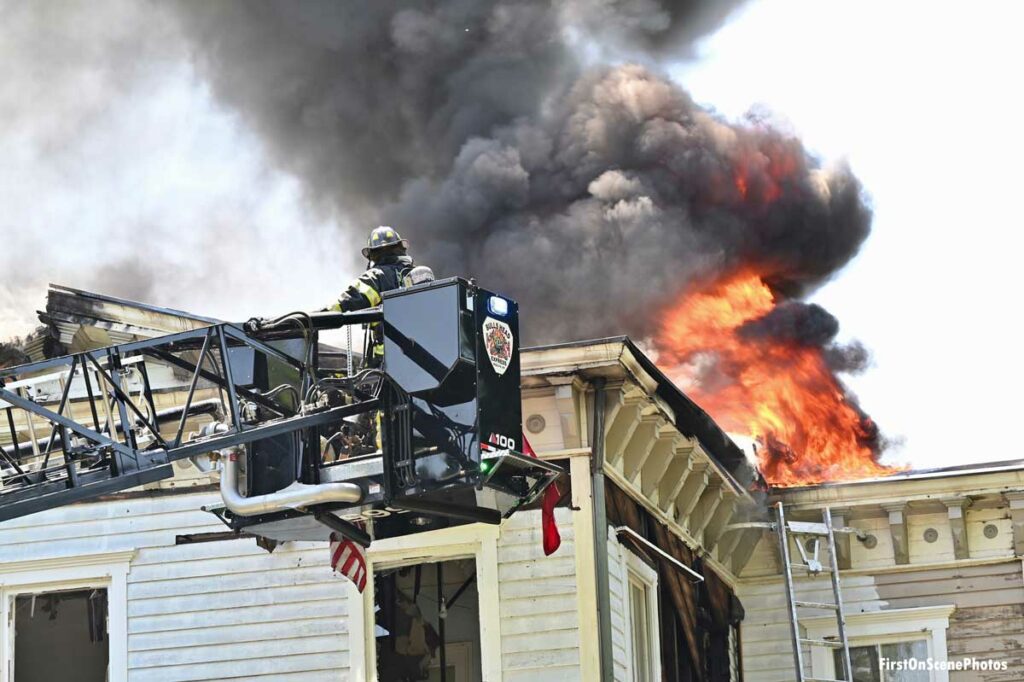 Firefighter in tower ladder bucket confronts flames and smoke at Sea Cliff house fire