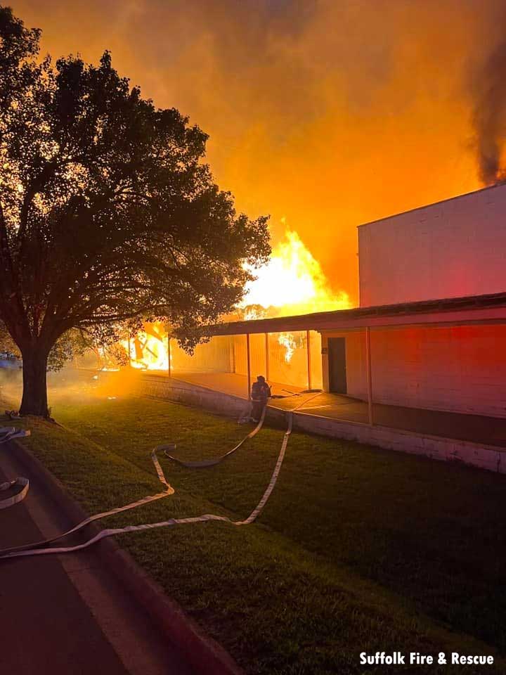 Firefighter moves hoseline toward commercial fire in Suffolk