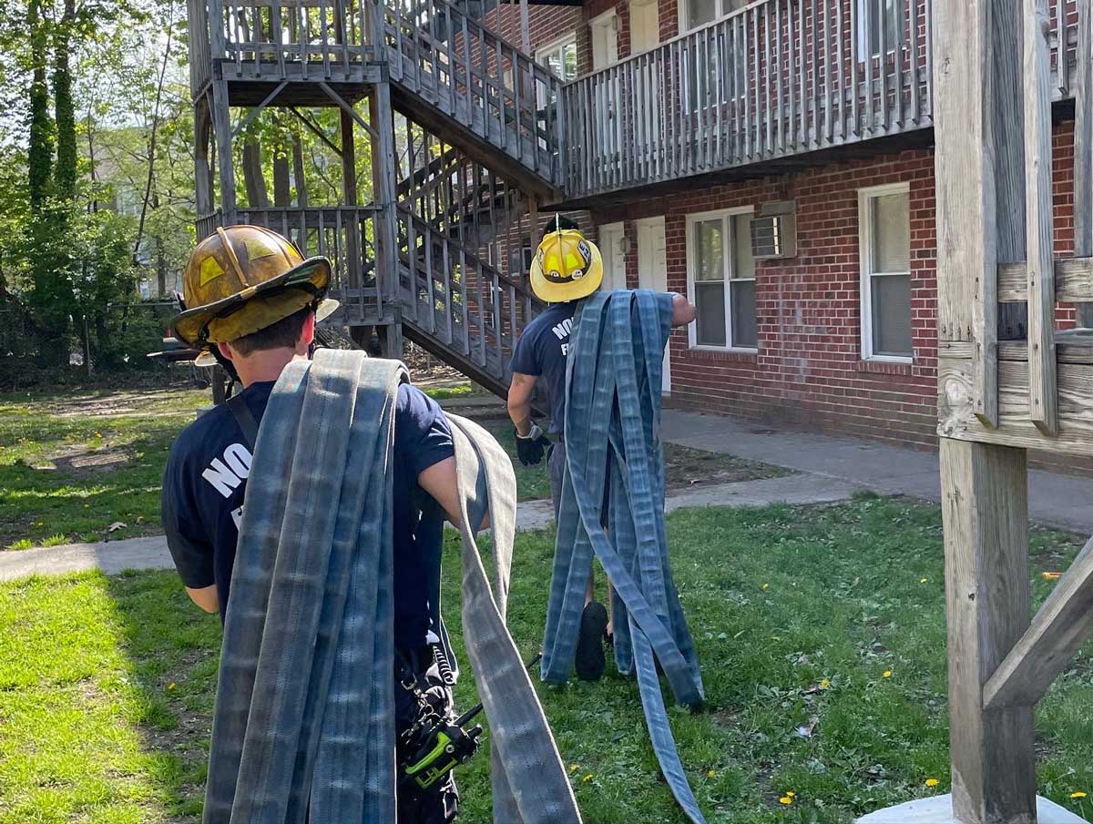 Norfolk firefighters with hose bundles on their shoulders