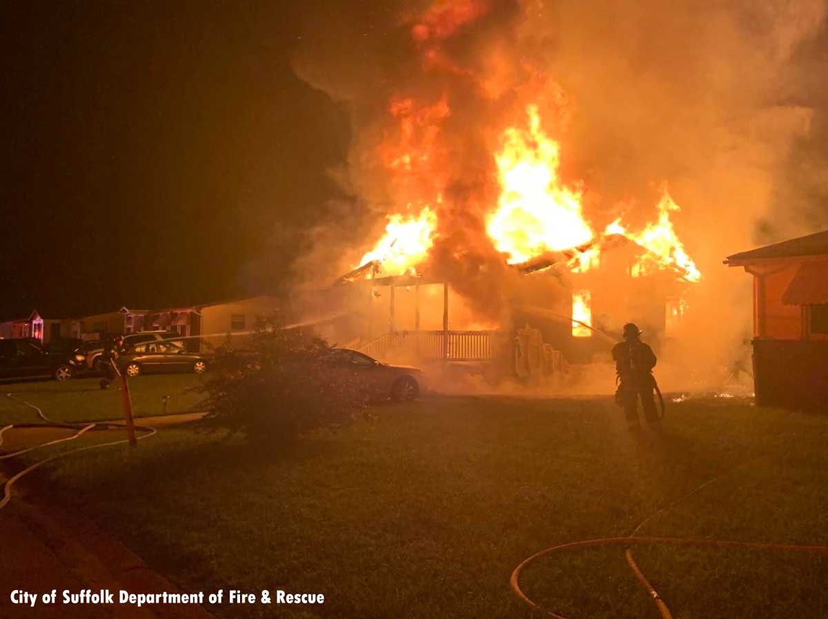 Firefighter on lawn putting water on Suffolk house fire