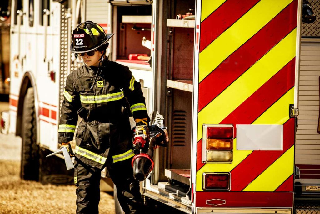 Firefighter taking tool out of truck compartment