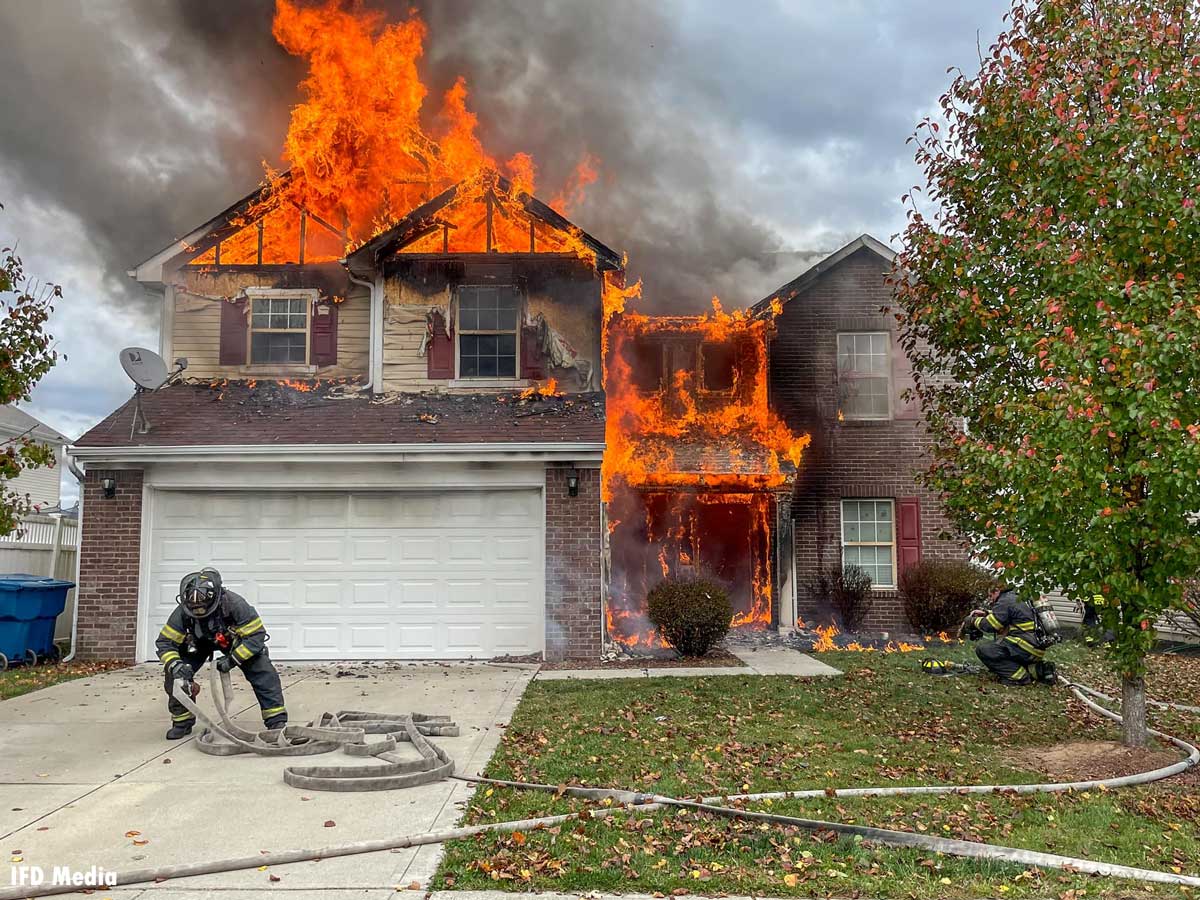 Indianapolis firefighter flakes out hoseline as flames roar through home