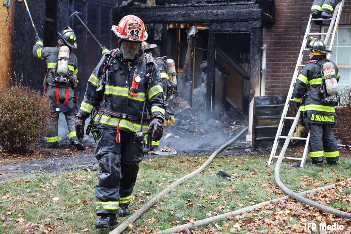 Indianapolis firefighter walks past hoselines