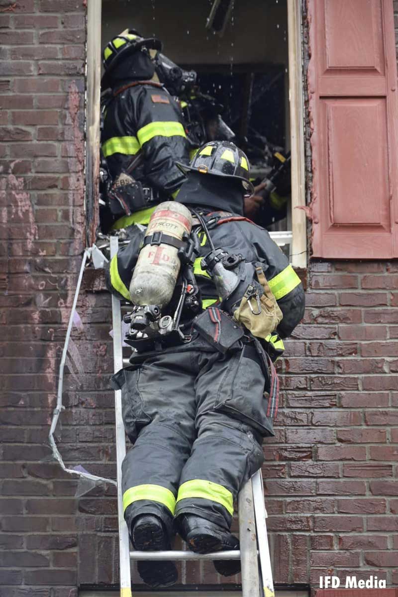 Indianapolis firefighters on a ladder during overhaul