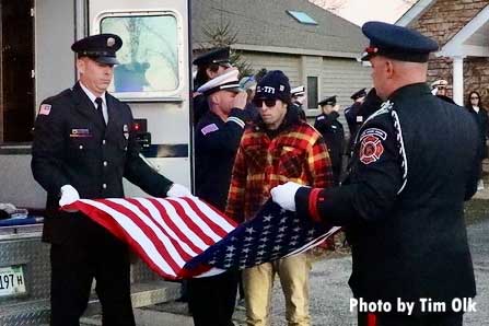 Firefighters with flag at memorial for firehouse canine