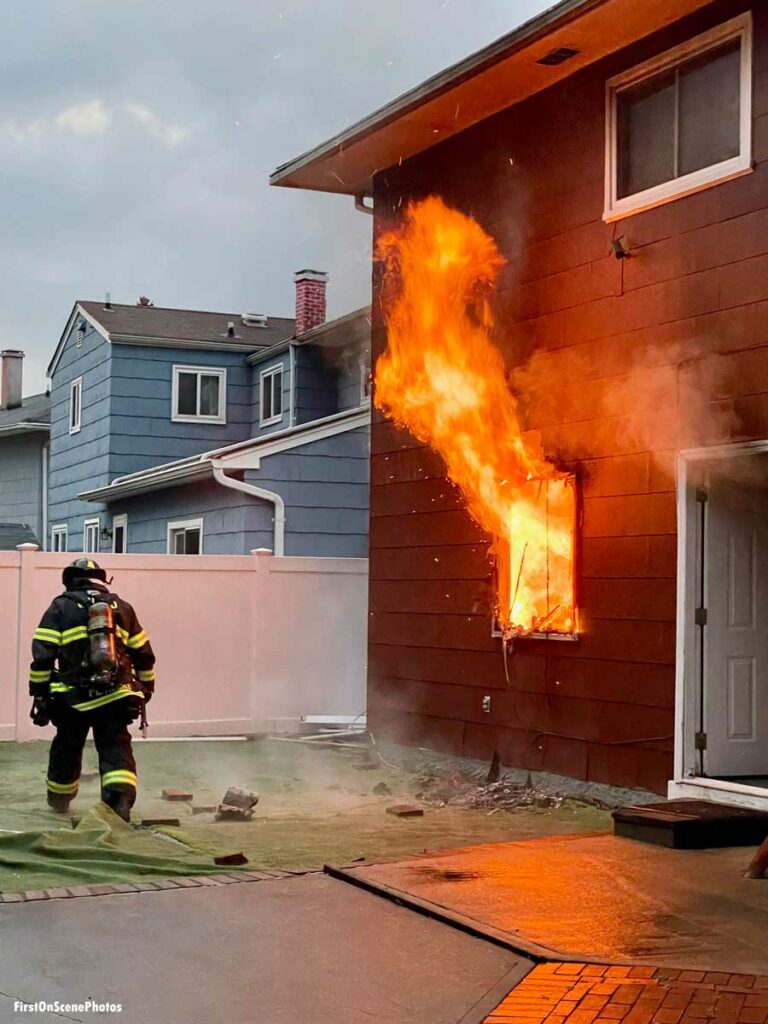 Firefighters with fire ventilating from window at Hempstead New York house fire