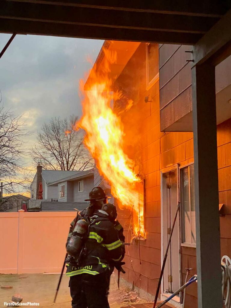 Firefighters with flame coming from D side window at Hempstead New York house fire