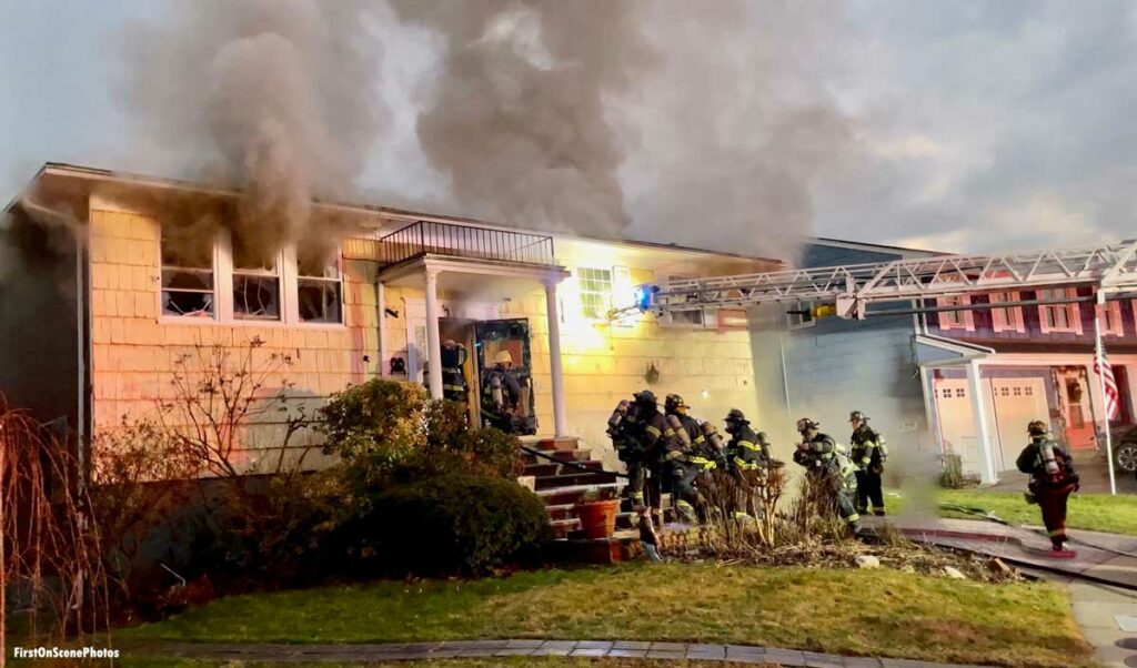 Smoke rises from windows as firefighters operate at Hempstead NY fire