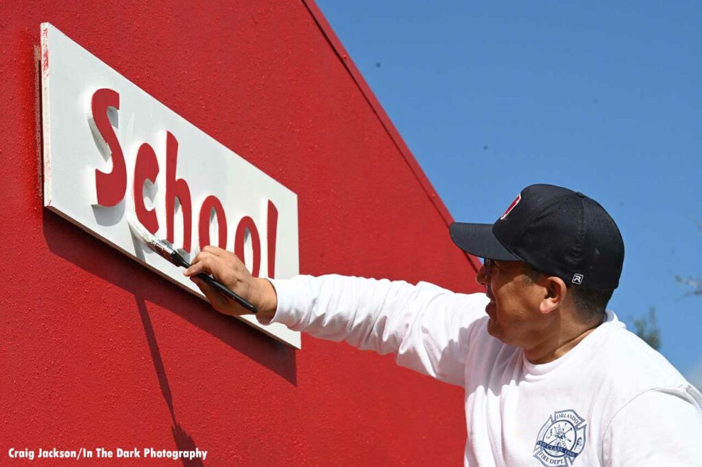 Orlando fire department member paints school sign