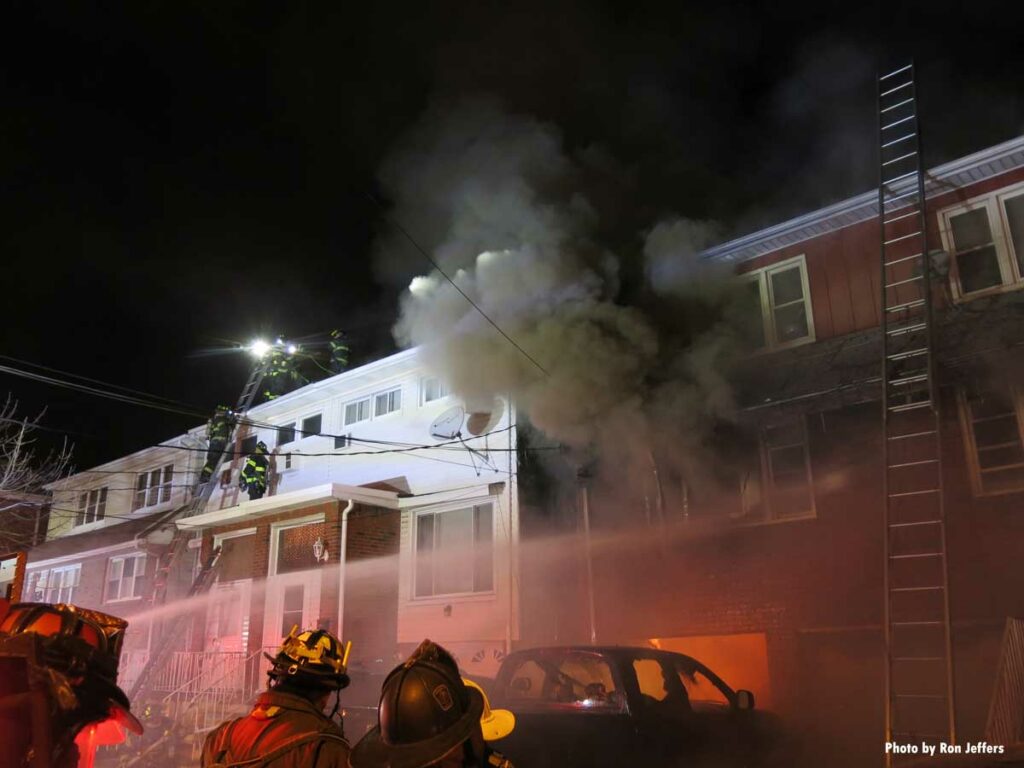 Firefighters make roof of ajoining building as smoke shoots from West New York fire