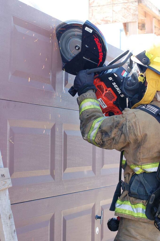 Firefighter cuts garage door with saw