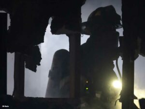 Firefighters navigates darkness inside structure with light