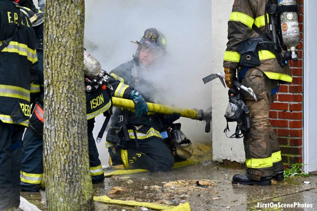 Firefighter advances hoseline through smoke at Floral Park fire