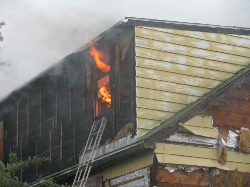 Fire vents from a window with ground ladder underneath