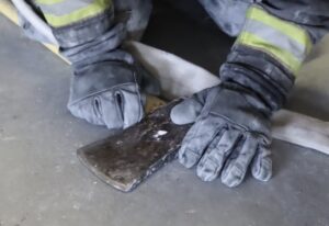 Firefighter hands gloves with ax and hose