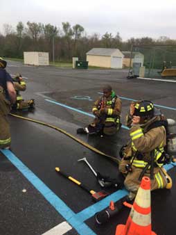 Firefighters with hose and tool during drill