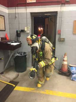 Firefighter in full gear with nozzle in training