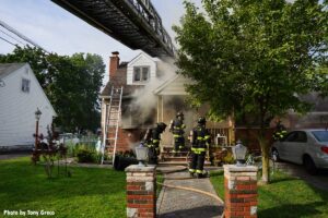 Firefighters with hoselines and ladder at Rochelle Park house fire