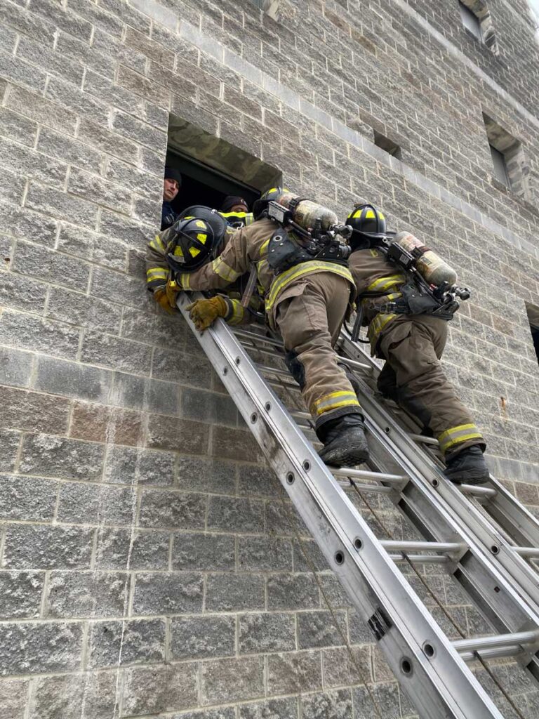 Two firefighters bring victim down set of two ladders